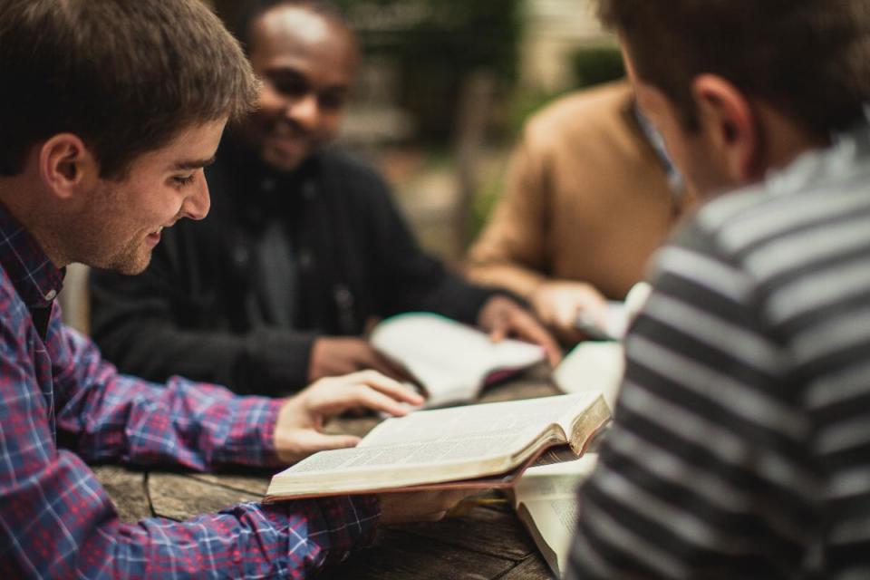 four men studying the BIble outside